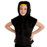 A young girl wearing a black hooded vest with a yellow bird headpiece, smiling at the camera.